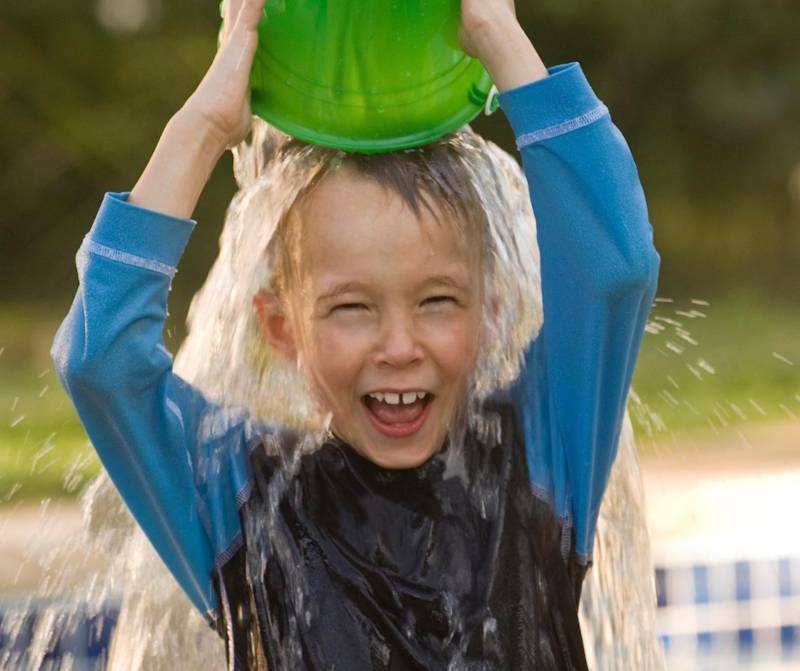 boy pouring bucket of water over his head